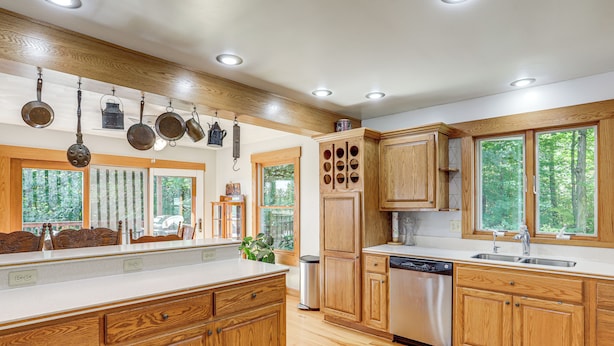 A kitchen with wooden cabinets, a dishwasher, and hanging pots. - Fish, Unplug & Unwind! Countryside Plymouth Home (Plymouth)