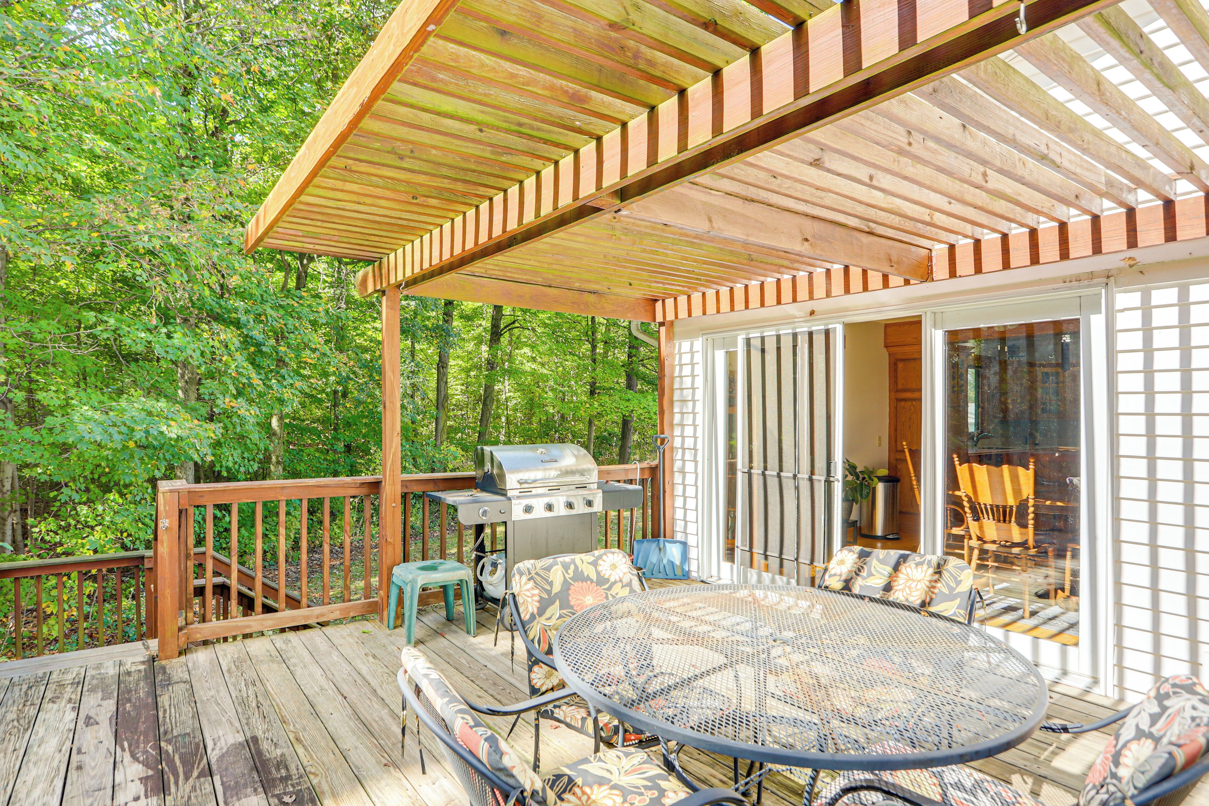 A wooden deck with a grill, outdoor furniture, and a glass door leading to a covered patio area.