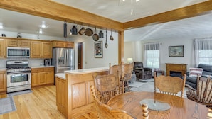 A spacious kitchen with wooden cabinets, stainless steel appliances, and a dining area with wooden chairs and a table. - Fish, Unplug & Unwind! Countryside Plymouth Home (Plymouth)