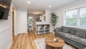 A modern living room with a sofa, a coffee table, and a kitchen in the background. - Valley Ridge Retreat - For 8 (Cincinnati)