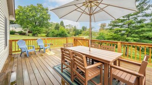 A wooden deck with a table and chairs, a large umbrella, and a view of a green landscape. - Valley Ridge Retreat - For 8 (Cincinnati)