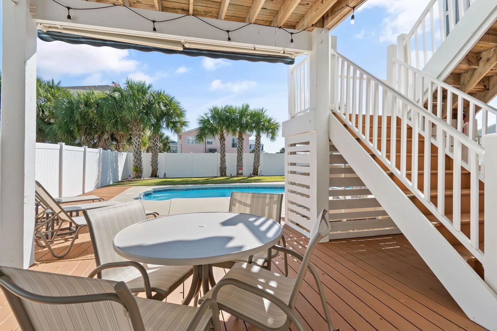 A covered outdoor area with a pool, wooden deck, and outdoor seating.