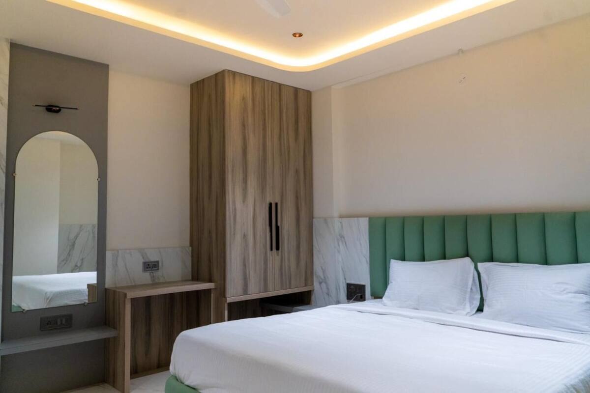 Un dormitorio con cama, armario, espejo y tocador con lavabo.
