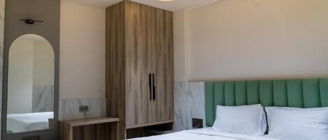 A bedroom with a bed, a wardrobe, a mirror, and a vanity with a sink.