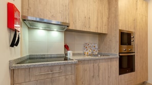 A modern kitchen with wooden cabinets, a stainless steel range hood, a microwave, and a built-in oven. - Setubal Boutique Apartments III by Homing (Setubal)
