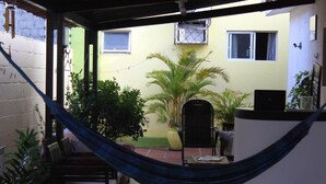 A covered outdoor area with a hammock, seating, and potted plants. - Pousada Zenite (Natal)