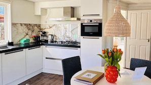 A modern kitchen with white cabinets, a Bosch oven, and a dining area with a round table and chairs.