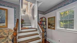 Eine Treppe mit Holzspindeln, ein Bücherregal und ein Gemälde an der Wand.