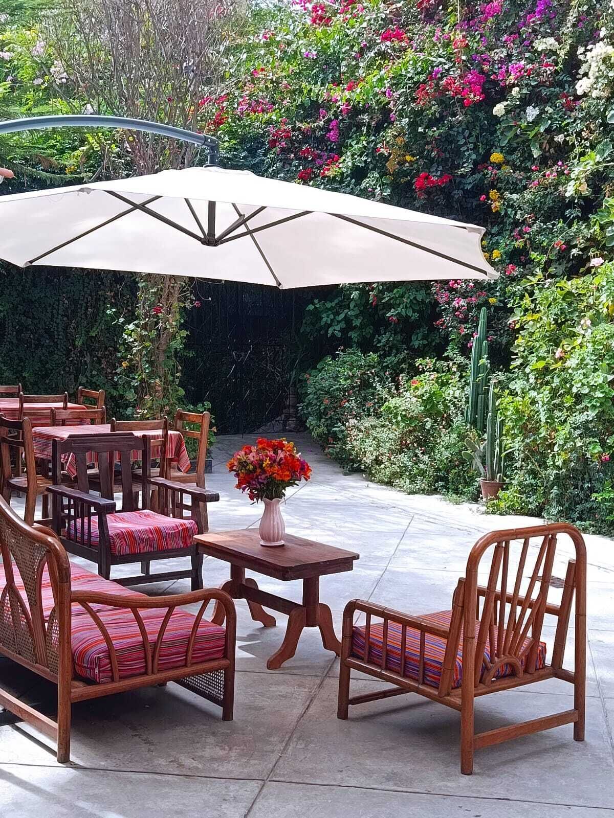 An outdoor patio with wooden furniture and a large umbrella.