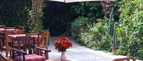 An outdoor patio with wooden furniture and a large umbrella.