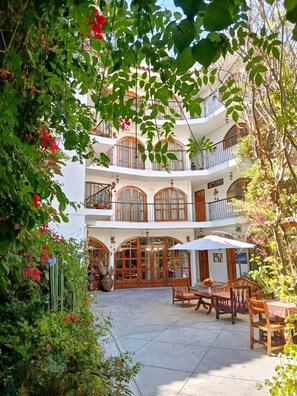 Un edificio a più piani con un cortile interno, arredo da esterno e piante rigogliose.