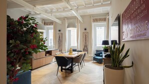 A spacious dining area with a wooden table and chairs, a potted plant, and a large wall-mounted sign. - THE BREAK - CAMPO MARZIO MAISON DELUXE (Roma)