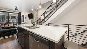 A modern kitchen with a dishwasher, a large island with a sink, and a staircase with a railing. - Beautiful multilevel townhome downtown Winter Park w/private rooftop hot tub (Winter Park)