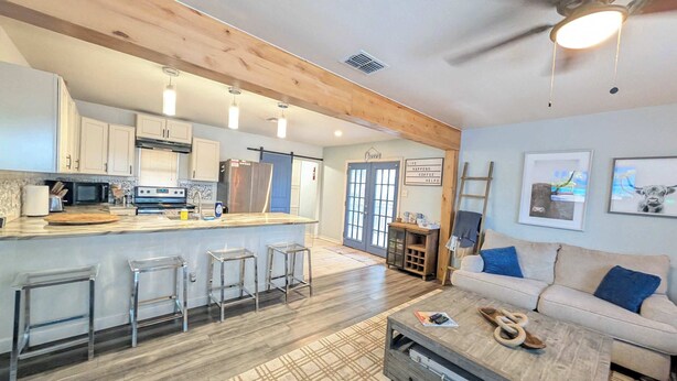 A modern kitchen with a central island, bar stools, and a dining area with a sofa and coffee table. - Sparkling City Stay S (Corpus Christi)