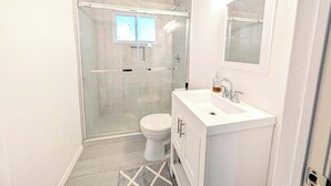 A modern bathroom with a glass-enclosed shower, a white sink, and a toilet. - Sparkling City Stay S (Corpus Christi)
