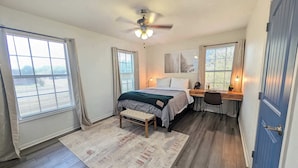 A bedroom with a bed, desk, chair, and a ceiling fan. - Sparkling City Stay S (Corpus Christi)