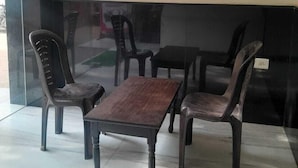 Un espace détente avec une table en bois et quatre chaises, une cloison en verre et un sol carrelé.