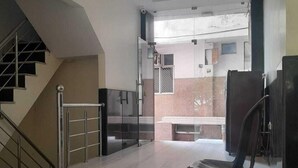 Une pièce spacieuse avec un plafond haut, un ventilateur de plafond, un escalier et une vue sur un bâtiment à l’extérieur.