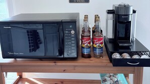 Keittiöalue, jossa on mikroaaltouuni, kahvinkeitin ja Torani-siirappipulloja puupöydällä.