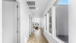 A hallway with white walls, wooden flooring, and large windows. - Tee For Two 6 Bedroom Condo (St. George)