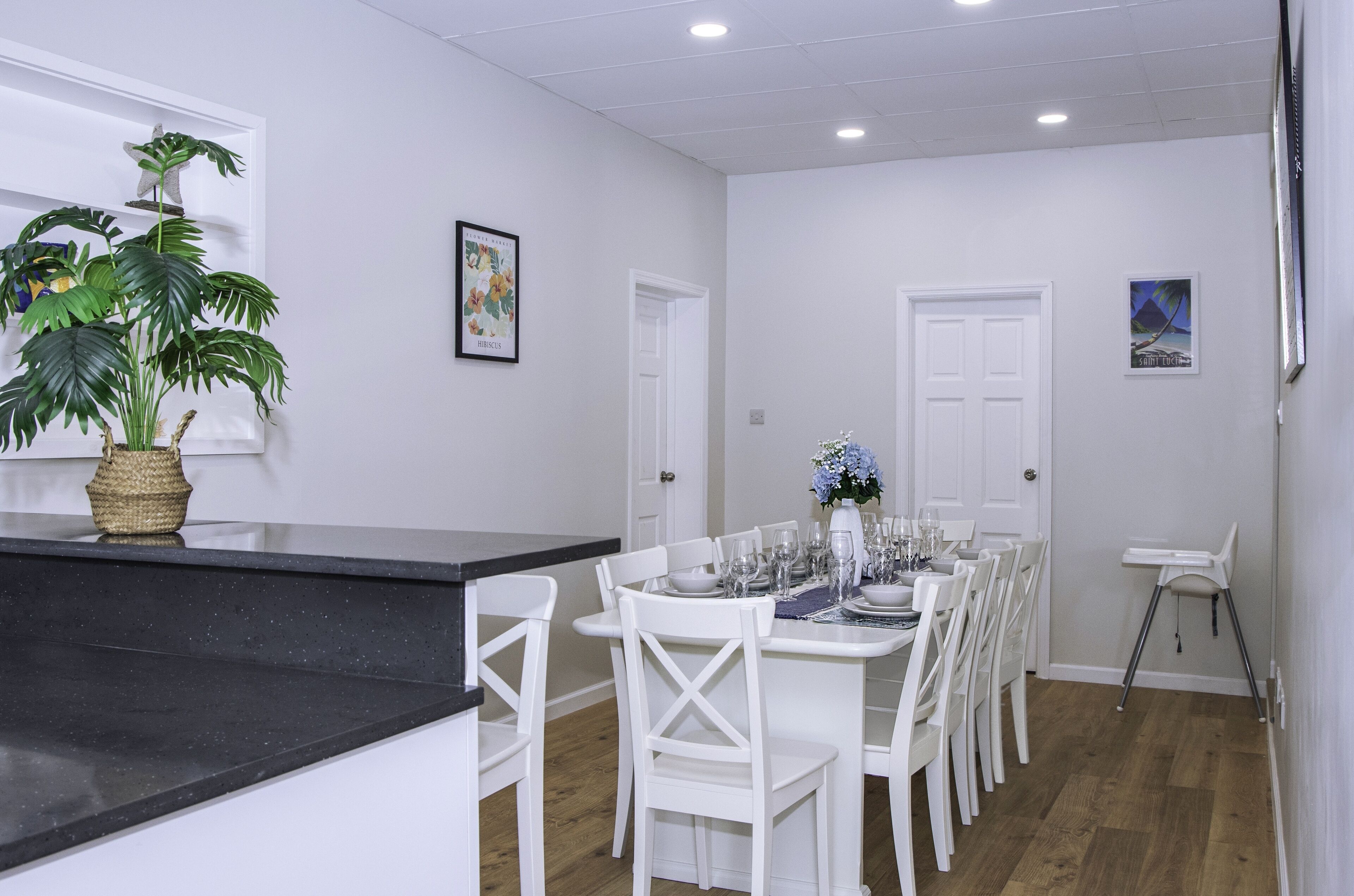 A dining area with a black countertop, white chairs, and a table set for four.