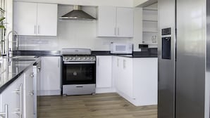A modern kitchen with white cabinets, a stainless steel stove, a microwave, and a refrigerator.