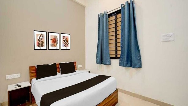 Une chambre à coucher bien rangée, avec un lit, une table de chevet, une fenêtre avec des rideaux et trois tableaux encadrés accrochés au mur.