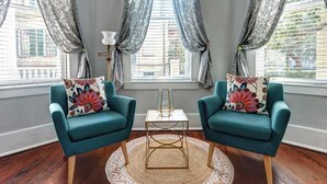 Una habitación con dos sillones turquesa, una mesita blanca y un tapete redondo tejido.