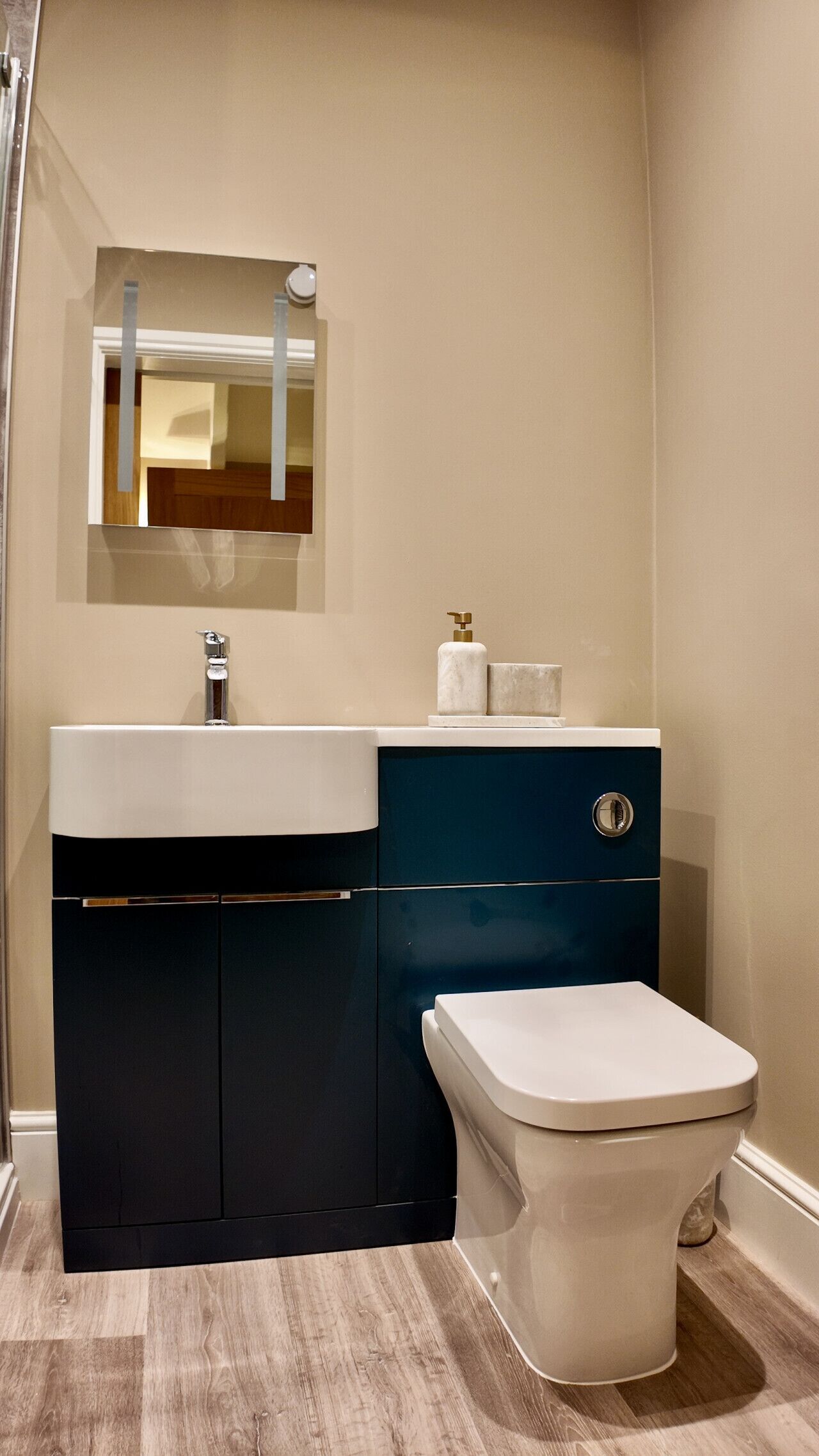 A modern bathroom with a white sink, dark blue cabinet, and a white toilet.