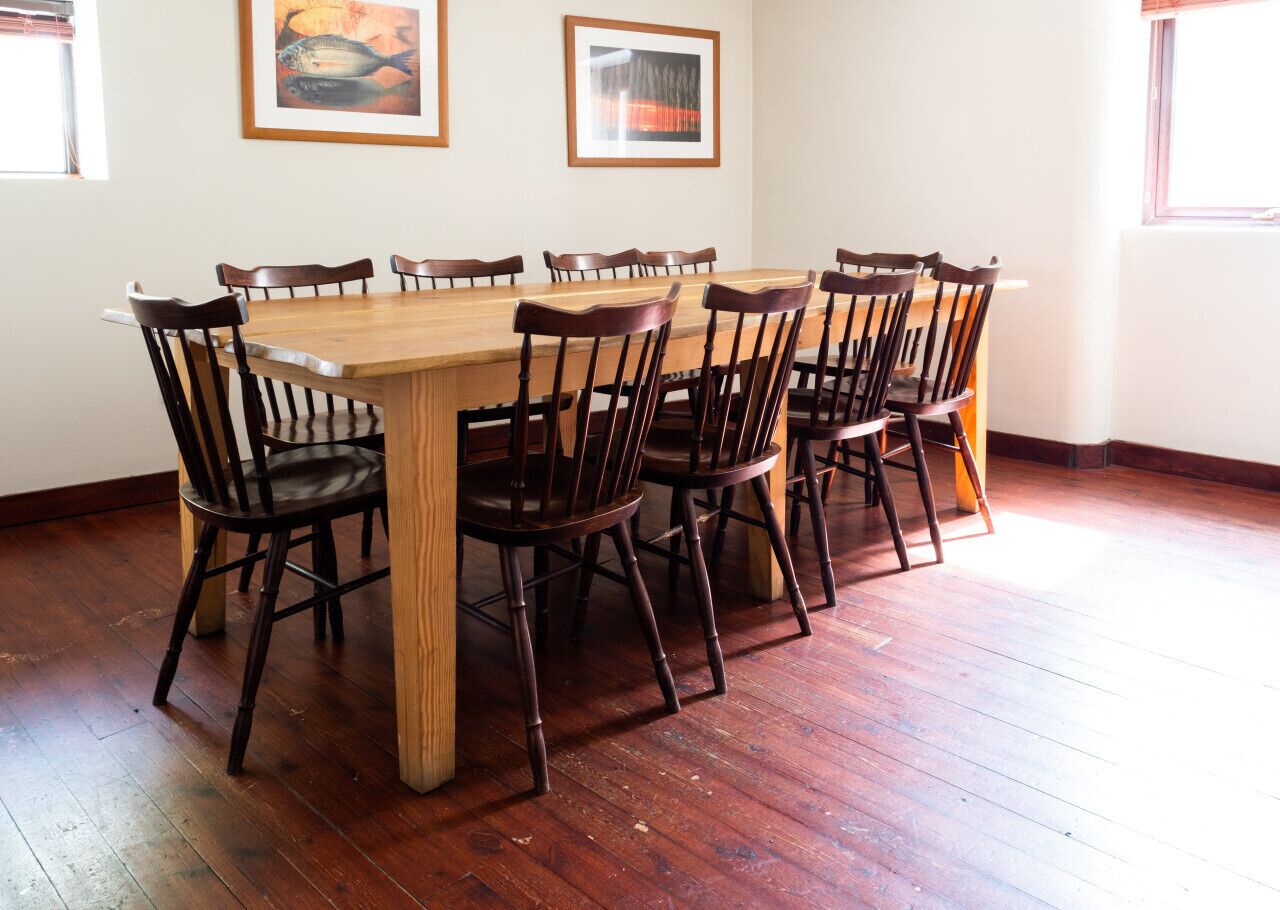 Un comedor con una mesa y sillas de madera, obras de arte en las paredes y suelo de madera.