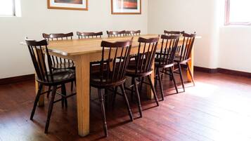 Un comedor con una mesa y sillas de madera, obras de arte en las paredes y suelo de madera.