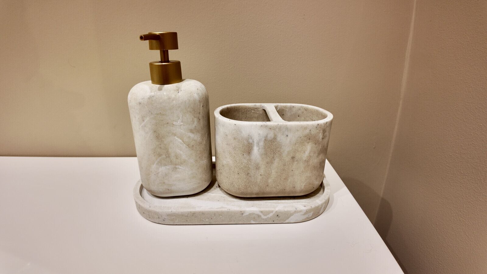 Un baño con lavamanos de mármol y dispensador de jabón.