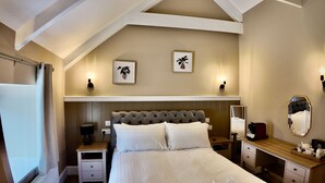 A bedroom with a large bed, bedside tables, a dresser, a mirror, and two wall-mounted lamps. - Rising Sun Inn - Kil Margh (Altarnun)