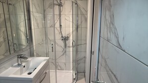 A modern bathroom with a glass-enclosed shower, a white sink, and marble flooring. - Modern 1-Bed Flat w/Garden|Pets & Families Welcome (Walton-on-Thames)
