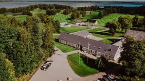 Campo de golf con club house, zona de estacionamiento y vistas a un lago.