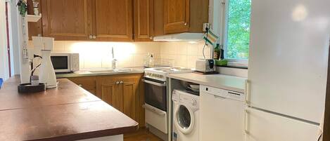 Une cuisine équipée de meubles en bois, d’un four à micro-ondes, d’un grille-pain, d’un lave-linge et d’un réfrigérateur.