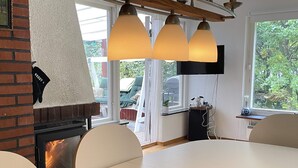 Una cocina moderna con chimenea de ladrillo, una mesa de comedor con bandeja de madera y lámparas colgantes.