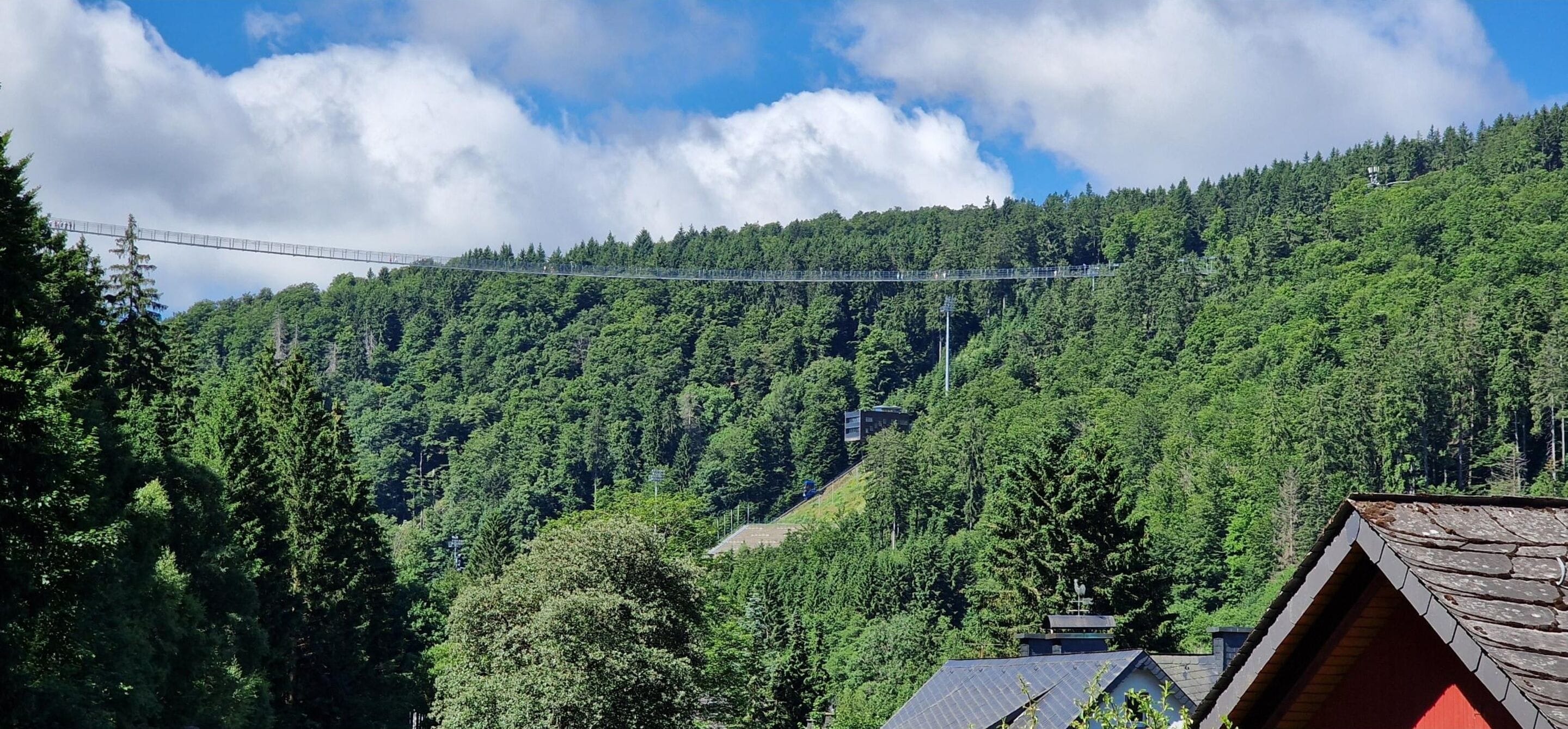 Un pont enjambant une montagne boisée, avec un ciel dégagé.
