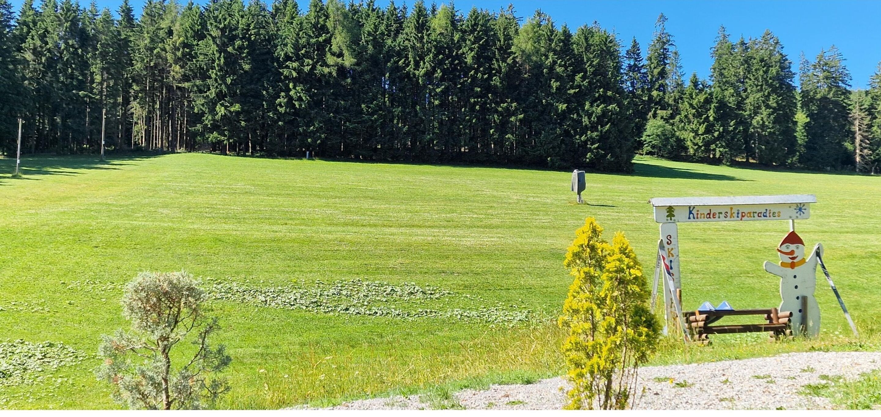 Un campo de golf con un cartel que dice 'Kinderparkades' y una decoración de muñeco de nieve.