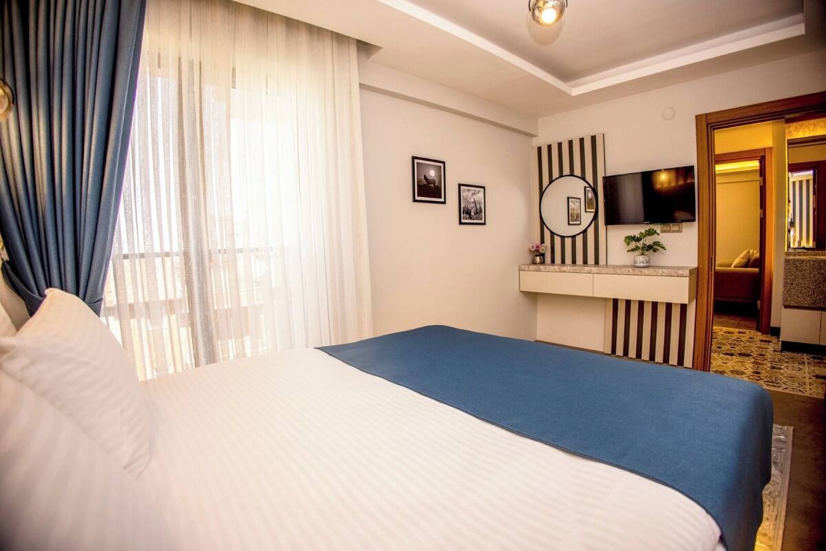 Une chambre d’hôtel avec un lit, un bureau doté d’un miroir et un téléviseur.