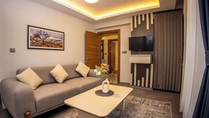 A modern living room with a sofa, a coffee table, a TV, and a painting on the wall. - newlifecappadocia (Nevşehir)
