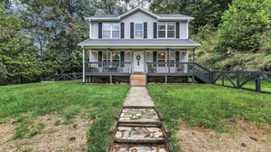 A two-story house with a front porch, a stone pathway leading to the door, and a wooden fence surrounding the property. - Ridgeview Retreat with Firepit and Mountain Views (Barnardsville)