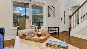 A cozy living room with a wooden coffee table, a book, and a wine bottle. - Ridgeview Retreat with Firepit and Mountain Views (Barnardsville)
