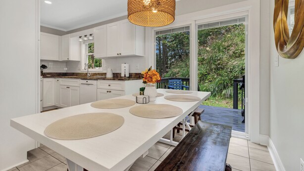 A modern kitchen with white cabinets, a large island with woven placemats, and a hanging light fixture. - Ridgeview Retreat with Firepit and Mountain Views (Barnardsville)