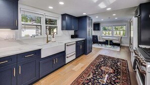 A modern kitchen with dark cabinets, white countertops, and a large rug.