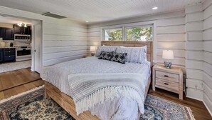 A bedroom with a wooden bed, a nightstand, a window, and a view of the outside.