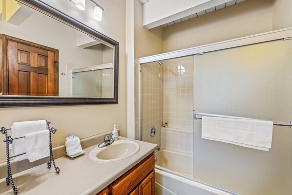 A bathroom with a wooden vanity, a sink, a mirror, and a glass-enclosed shower. - Powder Day Hideaway | Fireplace & Winter Shuttle (Steamboat Springs)