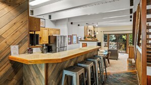 Una cocina moderna con barra de madera, electrodomésticos de acero inoxidable y vistas al patio exterior.