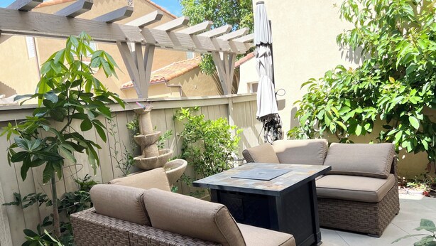 Une terrasse dotée de meubles en osier, d’une fontaine en pierre et d’une pergola.