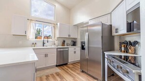 Una cocina moderna con armarios blancos, electrodomésticos de acero inoxidable y suelo de madera.